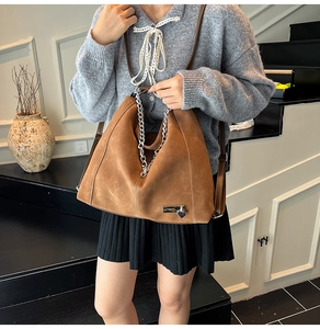 Brown suede tote bag detail featuring silver metal chain and a delicate heart charm
