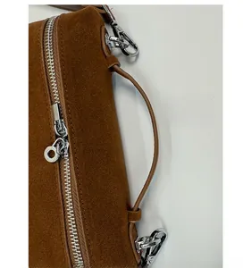 Detailansicht der braunen Wildledertasche mit silbernen Metallbeschlägen und Reißverschluss