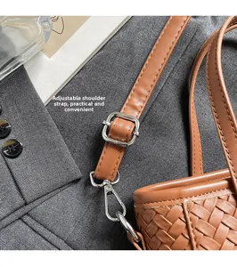 Detail of adjustable shoulder strap buckle on brown woven bucket bag with silver hardware