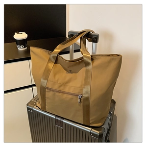 Détail d'un grand sac en tissu oxford kaki avec sangles posé sur une valise noire