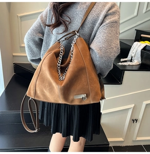 Detail of vintage brown suede tote bag with thick metal chain and heart charm accent