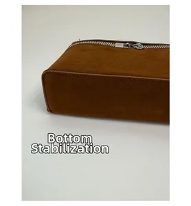 Detail einer braunen Wildleder-Umhängetasche mit Metallreißverschluss und Bodenverstärkung