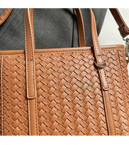 Close-up of brown woven leather texture with silver metal ring buckle on handbag