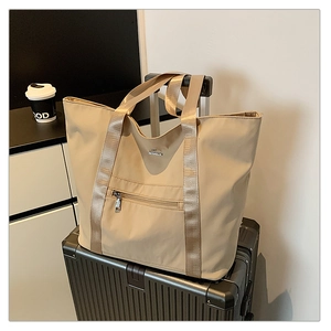 Détail du sac fourre-tout beige en tissu Oxford fixé sur la poignée d'une valise