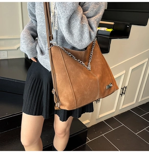 Detail of vintage brown suede tote bag with silver V-chain and metal logo tag