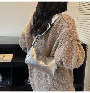 Detail of silver metallic hobo bag featuring wide shoulder strap and quilted stitching