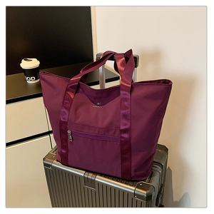 Détail du grand sac cabas violet en oxford imperméable posé sur une valise argentée