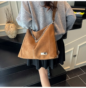 Detail of vintage brown suede tote with thick silver chain strap and metal buckle
