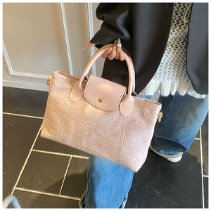 Dettaglio della borsa tote in tessuto rosa con patta in pelle e bottone dorato