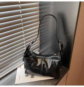 Close-up of the glossy patent leather texture and silver hardware of the black bag