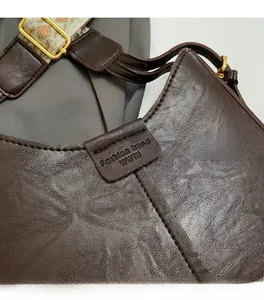 Detail of dark brown leather texture and gold hardware on a stylish bucket bag