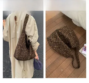 Detail view of large leopard print tote bag with wide straps shown on asphalt and wood
