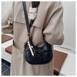 Detail of a black leather hobo bag with knotted strap and wooden beaded charm