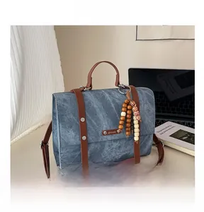 Vue détaillée du sac en jean avec poignées en cuir marron et breloques en perles de bois