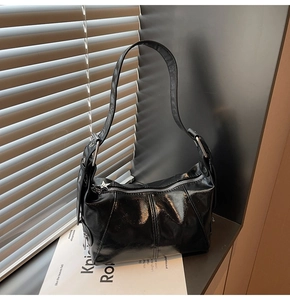 Detail of glossy black hobo bag featuring silver zipper and star-shaped metal pendant