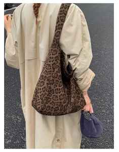 Outdoor street view of a large leopard print canvas tote bag styled with a trench coat