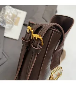 Detail of dark brown leather handbag featuring golden buckles and woven ethnic strap