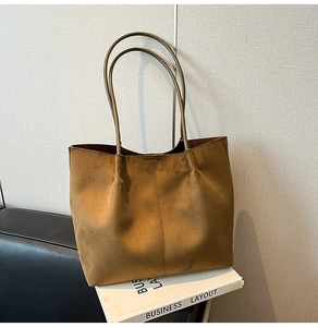 Detailed close-up of brown suede tote bag with reinforced stitching and dual shoulder straps