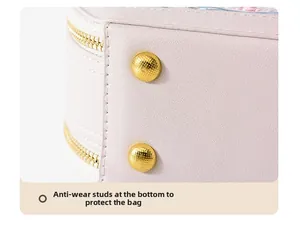 Detail of pink embroidered bag bottom with golden protective metal studs and litchi texture
