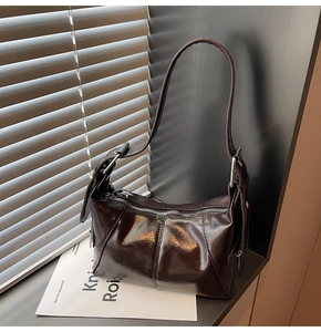 Detail view of glossy dark brown oil wax leather bag with star-shaped metal zipper puller