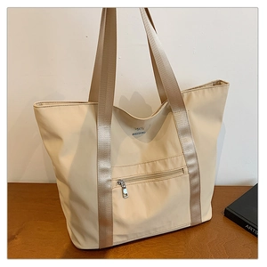Détail du sac cabas beige en nylon avec large bandoulière et poche zippée cachée