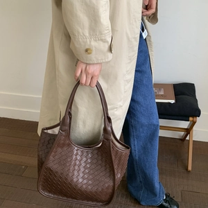 Close-up of deep brown woven leather tote bag with classic intrecciato weave detail