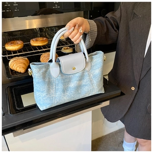 Dettaglio della borsa tote in denim azzurro con manici in pelle e chiusura magnetica dorata