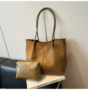 Minimalist tan faux suede tote bag with small olive green inner pouch set on a sofa