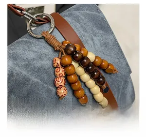 Détail d'un sac à dos en denim bleu avec lanière en cuir brun et glands en perles de bois
