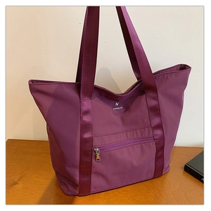Détail du sac fourre-tout violet en Oxford avec poche zippée argentée et logo en métal