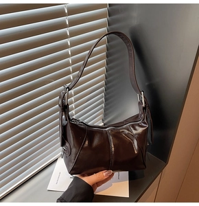 Detailed view of dark brown crescent bag featuring pleated texture and silver zipper