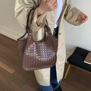 Close-up of brown woven leather tote bag with Intrecciato pattern and reinforced handles