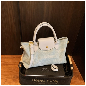 Dettaglio della borsa tote in denim azzurro con manici in pelle grigia e fibbie dorate