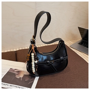 Detail of minimalist black hobo bag with vintage wooden beads and decorative buckle