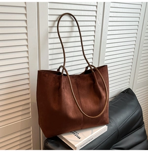 Detail of deep brown suede tote bag featuring fine stitching on black leather stool