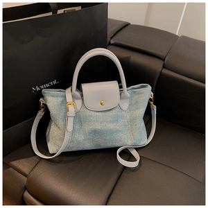 Dettaglio della borsa tote in denim azzurro con patta in pelle e fibbie in metallo oro