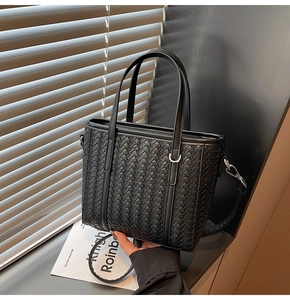Detail of black woven leather tote bag with sturdy handles and adjustable shoulder strap