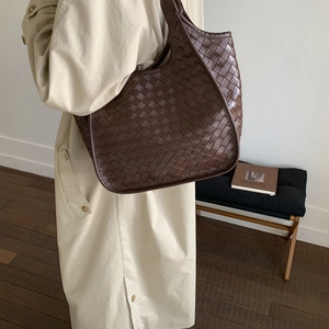Detail of premium brown leather woven tote bag showing the textured wide-strip craftsmanship