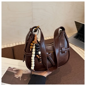 Close-up of retro dark brown crescent bag with unique wooden bead charm and belt buckle