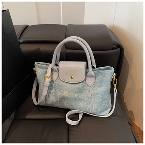 Dettaglio borsa in denim azzurro con manici in pelle grigia e fibbie in metallo dorato