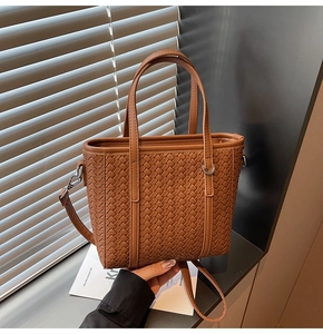 Detail shot of brown woven leather texture and silver hardware on a tote bag