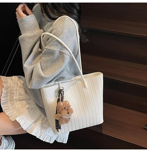 Detailed herringbone weave of a large white tote bag with a brown plush bear charm