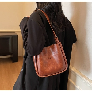 Detailed view of the brown vintage leather bucket bag texture and buckle on a model