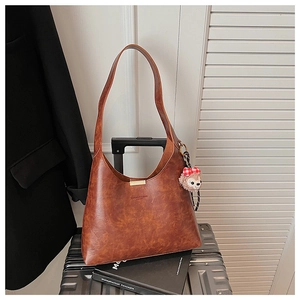 Detailed macro view of brown vintage hobo bag with oil wax texture and cute plush charm
