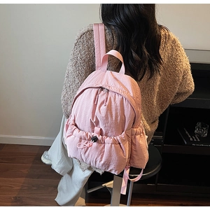 Close-up of pink nylon backpack featuring large drawstring front pocket and textured fabric