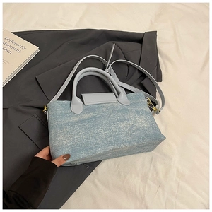 Dettaglio borsa tote in denim azzurro con anelli metallici dorati e tracolla coordinata