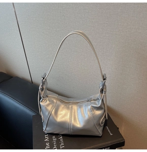 Close-up of the silver metallic shoulder bag showing premium texture and vertical stitching