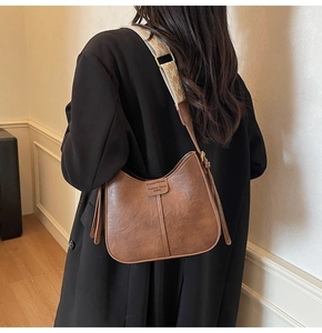 Back view of brown PU leather hobo bag with patterned woven strap on black blazer
