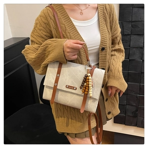 Détail du sac à main minimaliste avec pompon en perles de bois et rivets métalliques
