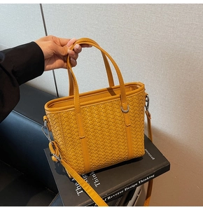 Detailed leather weaving texture on yellow bucket bag with silver metal hooks and strap